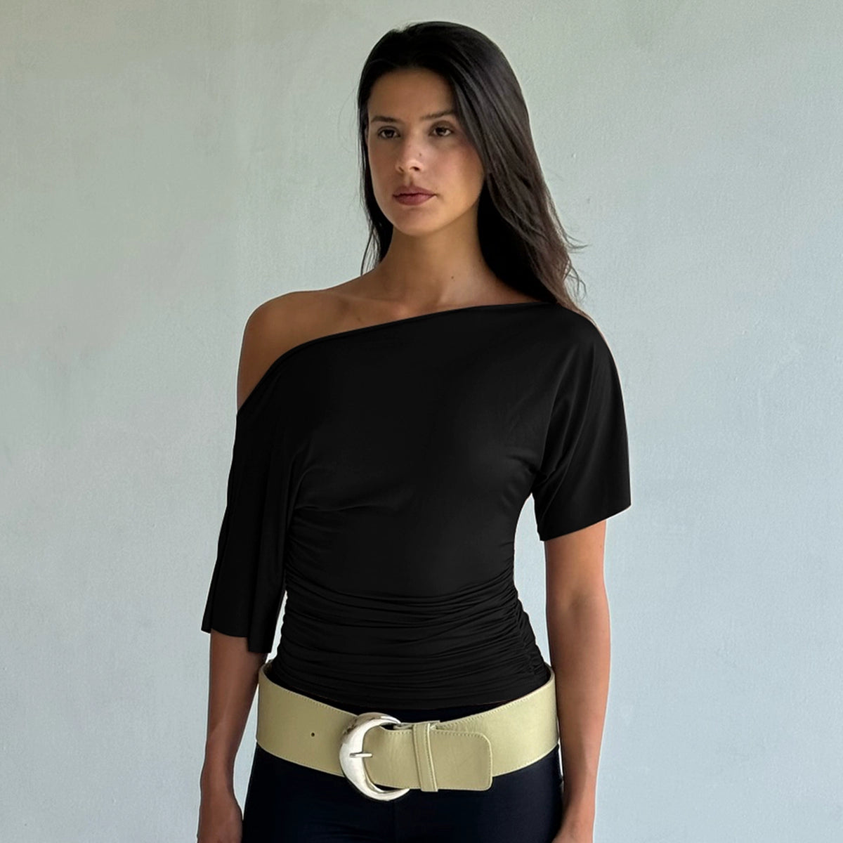 Shemoda: Noir Serene Top | Nüra - Discover Shemoda's Noir Serene Top: a sleek, stylish T-shirt with slanted shoulder and ruched waist for a modern, confident look. Perfect for any occasion. - $18.00