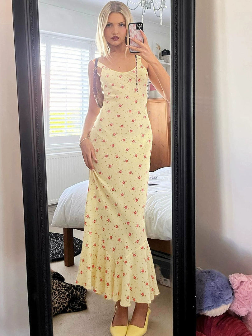 Shemoda: Raya Sundress | Nüra - Discover Shemoda's Raya Sundress: a sleeveless yellow floral dress with a scoop neck and fishtail hem, perfect for elegant warm-weather events. - $20.00