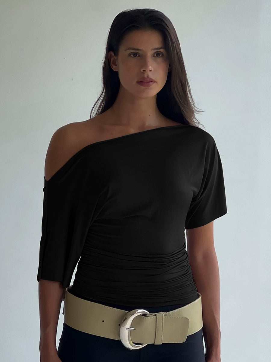 Shemoda: Noir Serene Top | Nüra - Discover Shemoda's Noir Serene Top: a sleek, stylish T-shirt with slanted shoulder and ruched waist for a modern, confident look. Perfect for any occasion. - $18.00