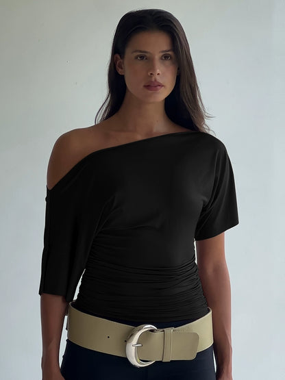 Shemoda: Noir Serene Top | Nüra - Discover Shemoda's Noir Serene Top: a sleek, stylish T-shirt with slanted shoulder and ruched waist for a modern, confident look. Perfect for any occasion. - $18.00