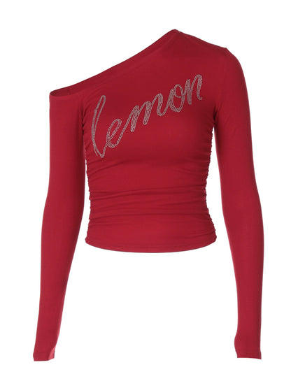 Shemoda: Zane Sparkle Top | Nüra - Shop Shemoda's Zane Sparkle Top: a vibrant, asymmetric crop with rhinestone "lemon" script. Stand out in style with this bold, one-shoulder design. - $19.00