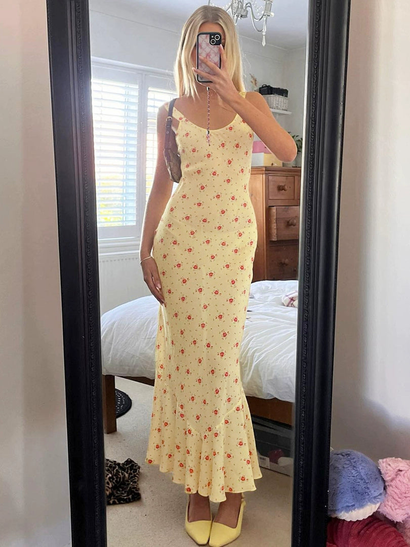 Shemoda: Raya Sundress | Nüra - Discover Shemoda's Raya Sundress: a sleeveless yellow floral dress with a scoop neck and fishtail hem, perfect for elegant warm-weather events. - $20.00