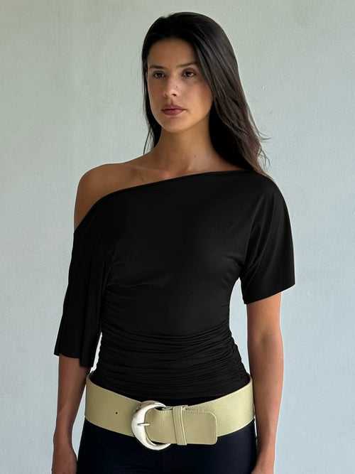 Shemoda: Noir Serene Top | Nüra - Discover Shemoda's Noir Serene Top: a sleek, stylish T-shirt with slanted shoulder and ruched waist for a modern, confident look. Perfect for any occasion. - $18.00
